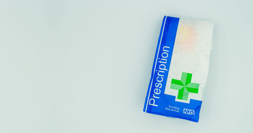 A British NHS prescription paper bag isolated on a white background|